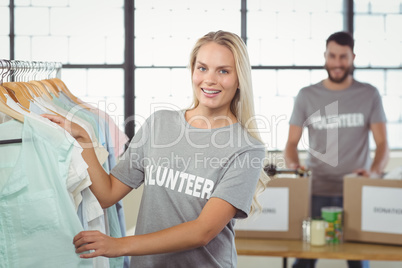 Portrait of happy volunteer choosing clothes for donation