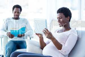 Smiling woman looking at tablet with man reading book