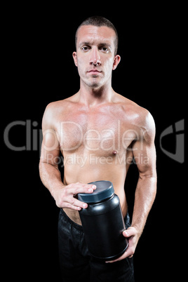 Portrait of confident shirtless man holding nutritional suppleme