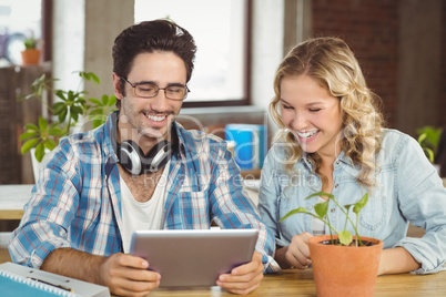 Happy business people laughing while looking at digital tablet a