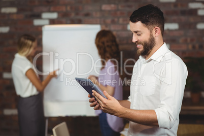 Young businessman holding tablet with colleagues discussing in b