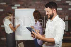 Young businessman holding tablet with colleagues discussing in b
