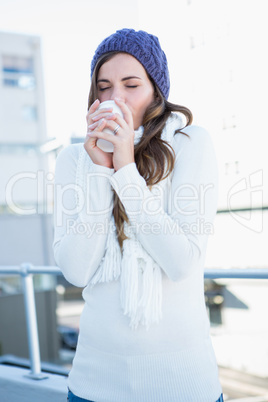 Cold brunette in warm clothes drinking coffee