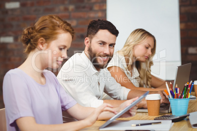 Portrait of smiling man sitting amidst colleagues