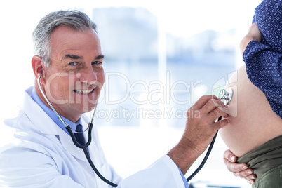 Portrait of male doctor examining pregnant woman in clinic