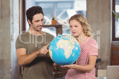 Colleagues looking at globe in office