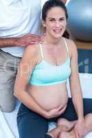 Happy pregnant woman with trainer in gym