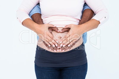 Midsection of couple making heart shape on belly