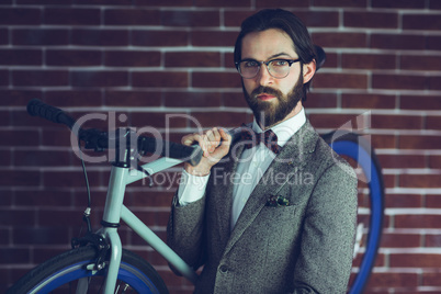 Portrait of smart confident hipster carrying bicycle