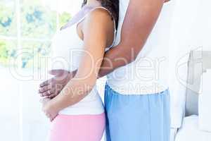 Side view of pregnant wife with husband touching belly