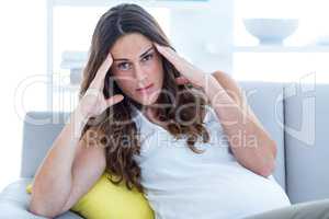Depressed pregnant woman sitting in living room