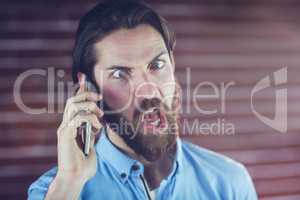 Hipster making a face while talking on cellphone