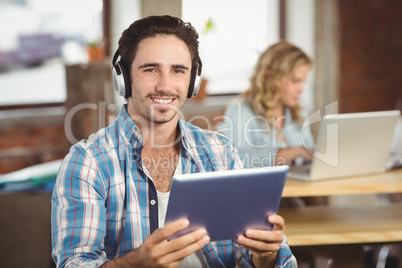 Portrait of happy businessman holding tablet in office