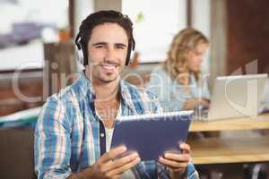 Portrait of happy businessman holding tablet in office