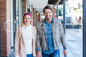 Smiling couple with shopping bags holding hands