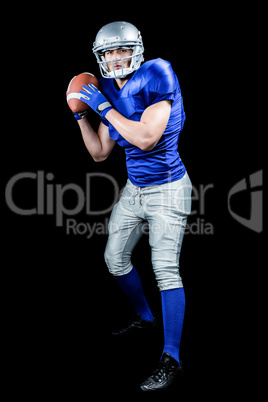 American football player throwing ball over black background