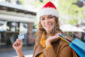 Portrait of smiling woman with santa hat and shopping bags