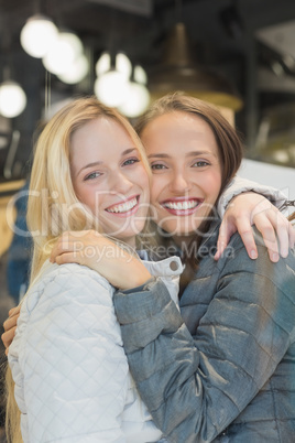 Two female friends with winter clothes smiling at camera