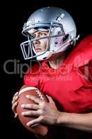 Determined American football player looking away while holding b