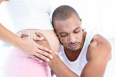 Man listening to belly of pregnant wife