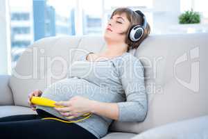 Pregnant woman listening to music with eyes closed