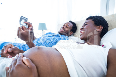 Happy man showing ultrasound scan to woman