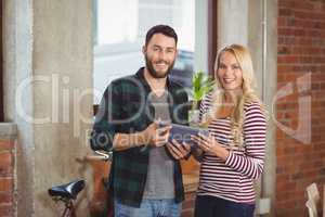 Smiling creative colleagues holding digital tablet