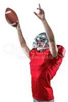 American football player holding ball while pointing up