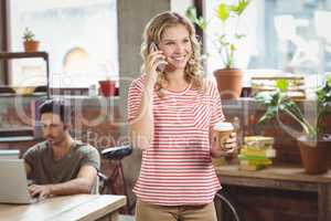 Happy businesswoman talking over phone while holding coffee in o