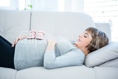 Side view of pregnant woman with baby shoes on belly