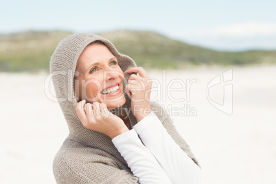 Smiling woman standing on the sand with hood up