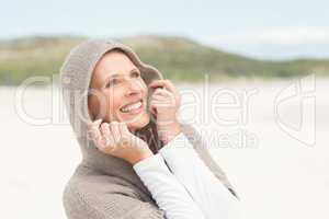 Smiling woman standing on the sand with hood up