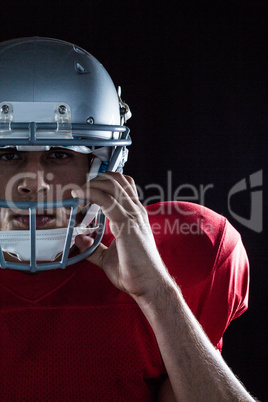 Portrait of American football player holding helmet