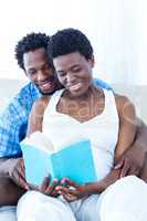 Pregnant woman and her husband reading book