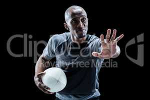 Serious sportsman gesturing while holding rugby ball