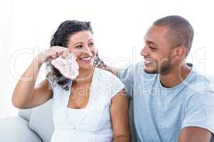 Cheerful woman showing baby footwear to husband