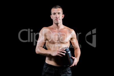 Confident shirtless man holding nutritional supplement