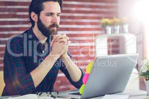 Focused editor with hand clasped using laptop