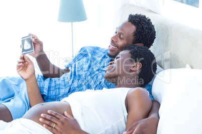 Couple looking at ultrasound scan while relaxing