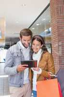 Young couple smiling while looking at tablet