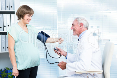 Doctor checking blood pressure of pregnant woman