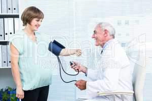 Doctor checking blood pressure of pregnant woman