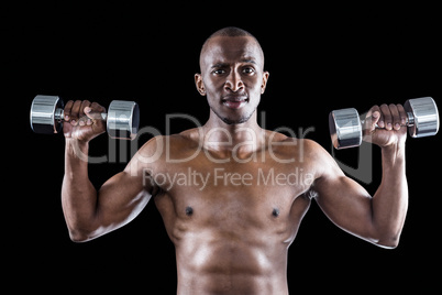 Portrait of athlete lifting dumbbell while exercising