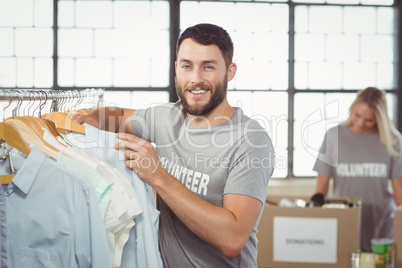 Portrait of happy man choosing clothes for donation