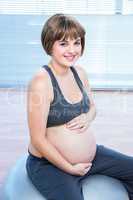 Portrait of happy pregnant woman sitting on fitness ball