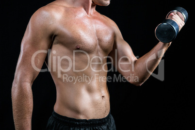 Midsection of shirtless athlete working out with dumbbell