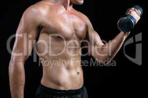 Midsection of shirtless athlete working out with dumbbell