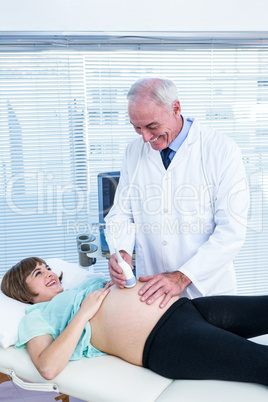 Happy doctor performing ultrasound on pregnant woman