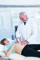 Happy doctor performing ultrasound on pregnant woman