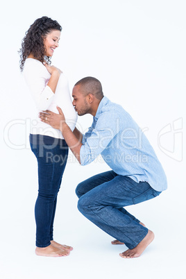 Husband kissing belly against white background